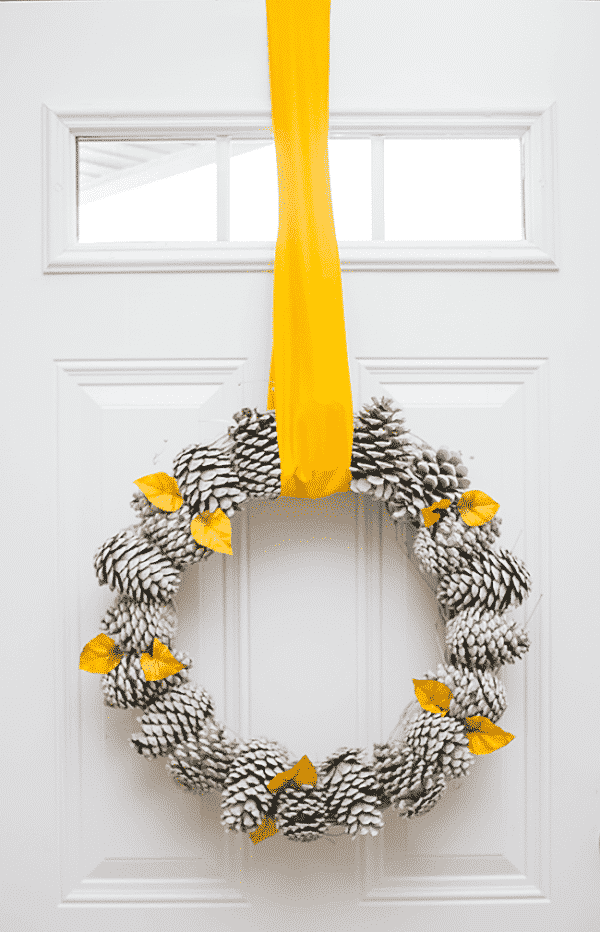 Pretty Pine Cone Wreath DIY hung fro door with yellow ribbon
