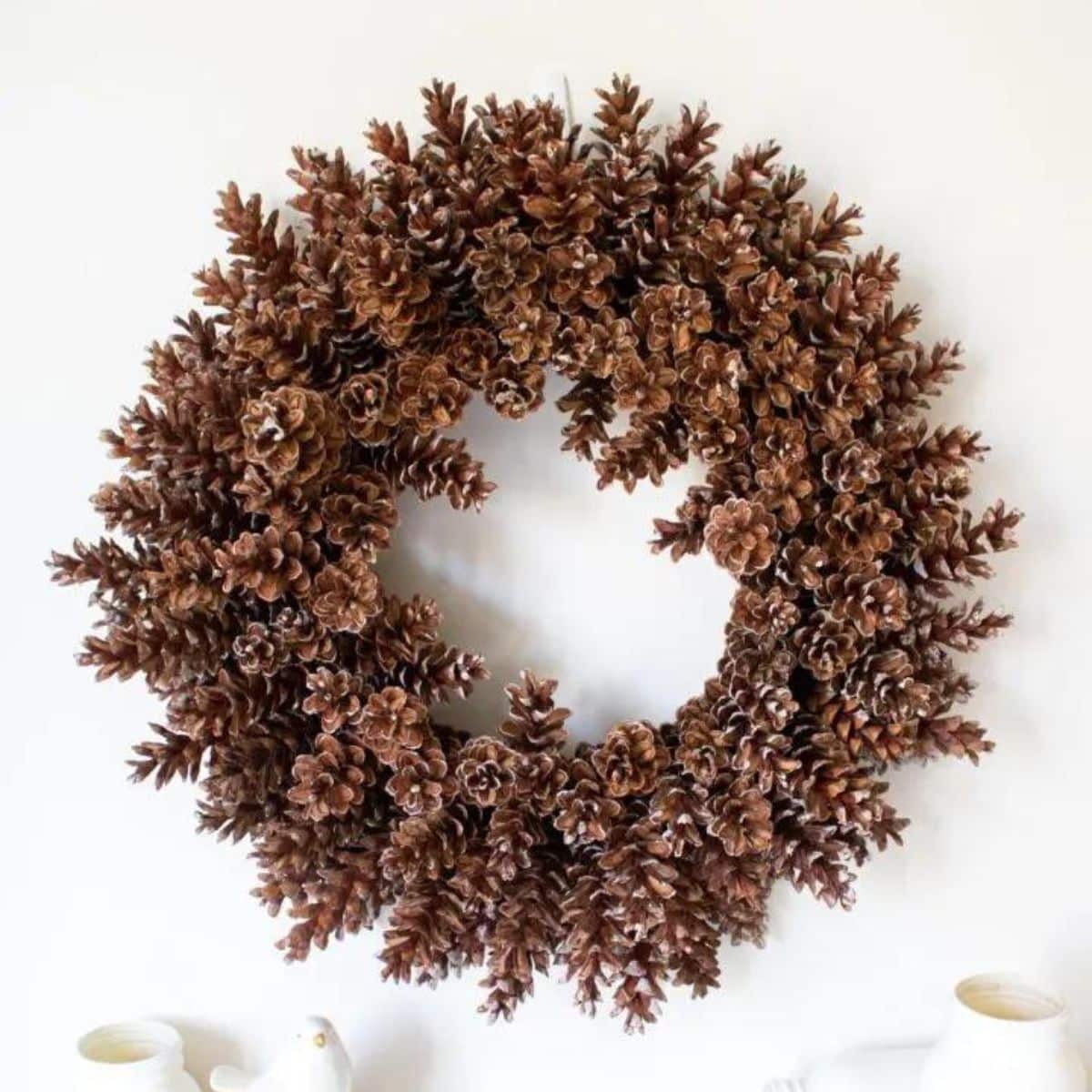 pine cone wreath hung on a white wall