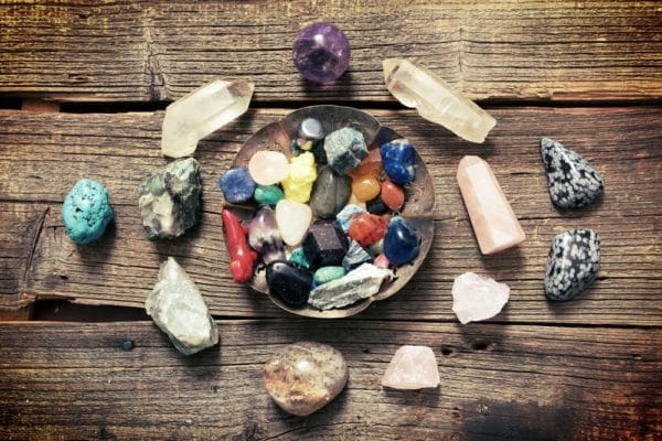 multiple semi-precious gemstones sit in a bowl with other surrounding them