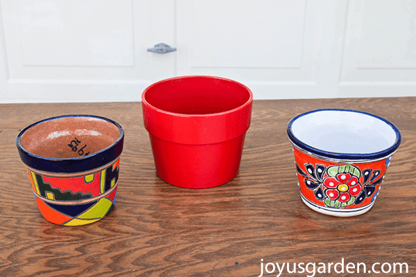 2 small colorful talavera pots sit on a table with a small colorful red pot in between