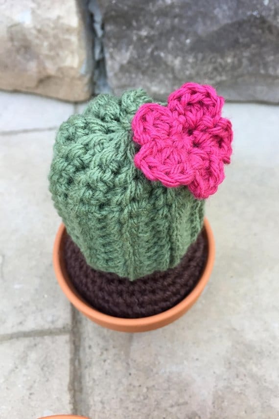 a small crochet cactus with a pink flower in a clay pot