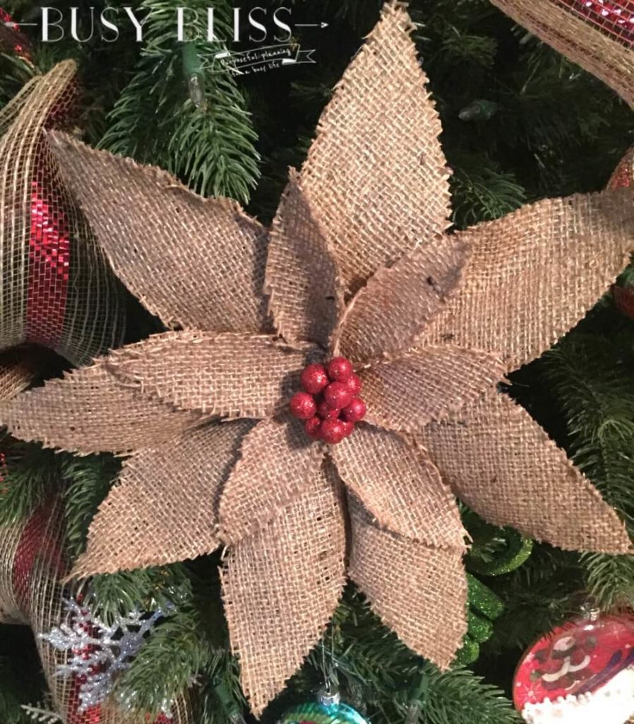 close up of a tan burlap poinsettia flower with a red center