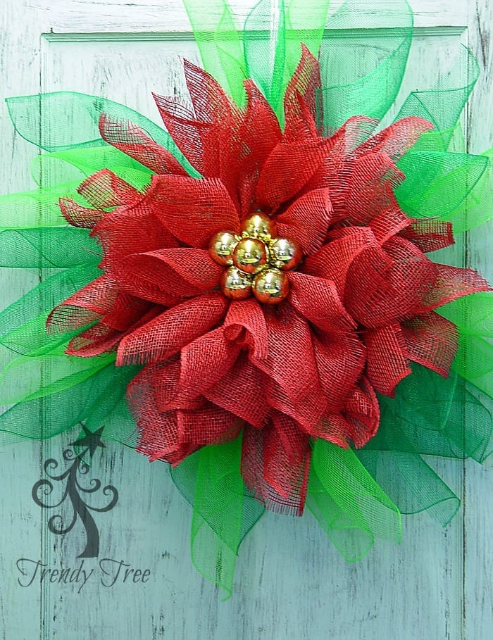 close up of a green mesh & red burlap poinsettia on a door
