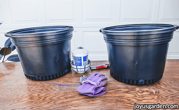 2 large black grow pots sit on a wooden potting table