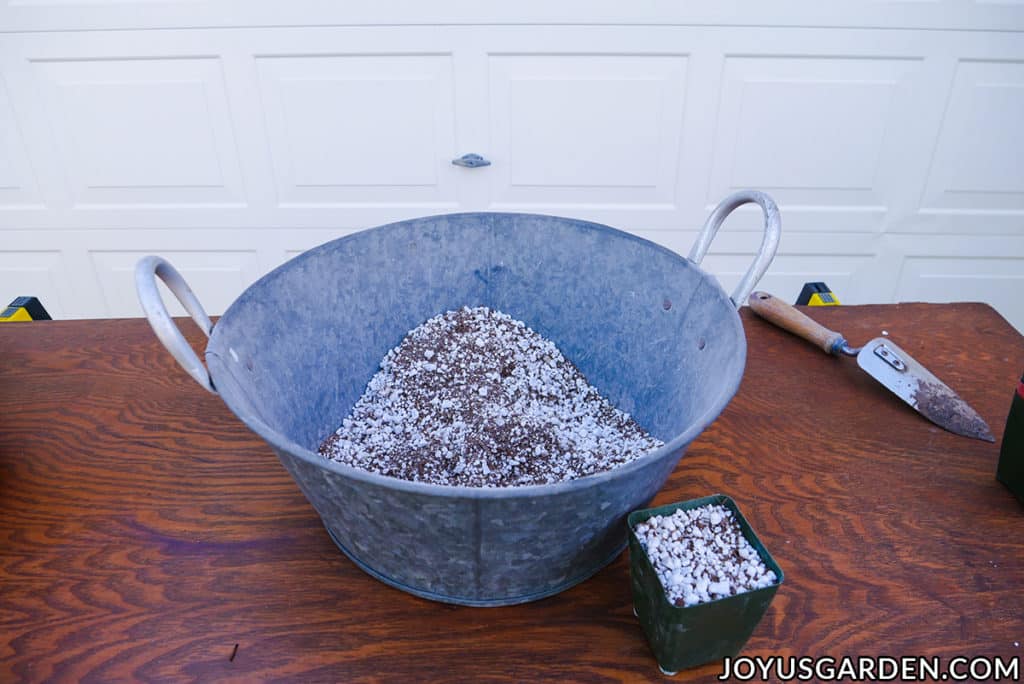 a large metal bin filled with diy seed starting mix sits next to a 4" grow pot