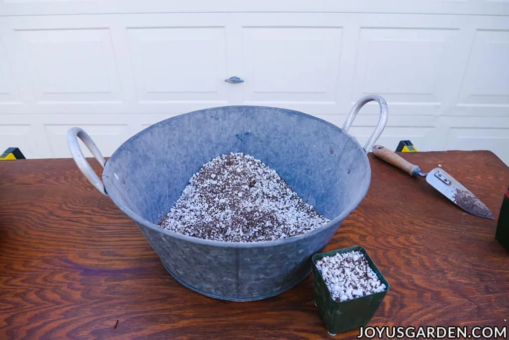 a large metal bin filled with diy seed starting mix sits next to a 4" grow pot