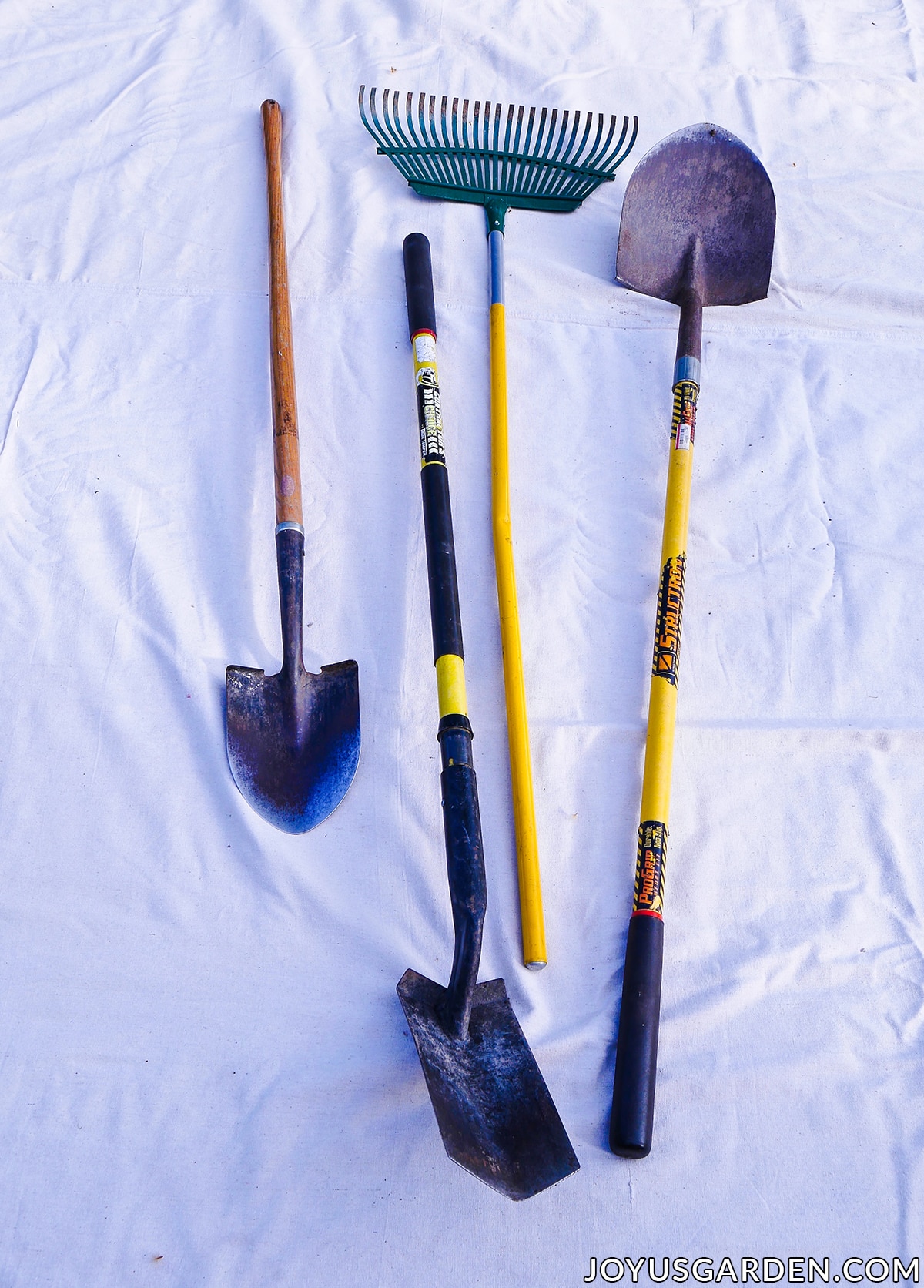 Three different shovels & a rake used for gardening.