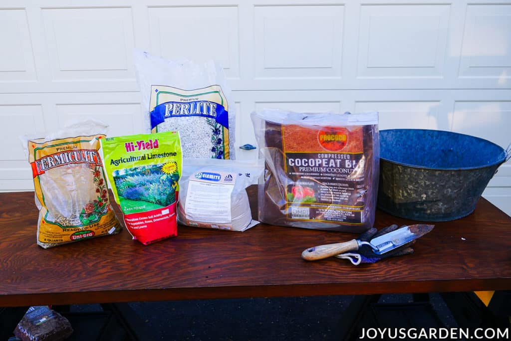 bags of ingredients used to make seed starting mix sit next to a trowel & a metal bin