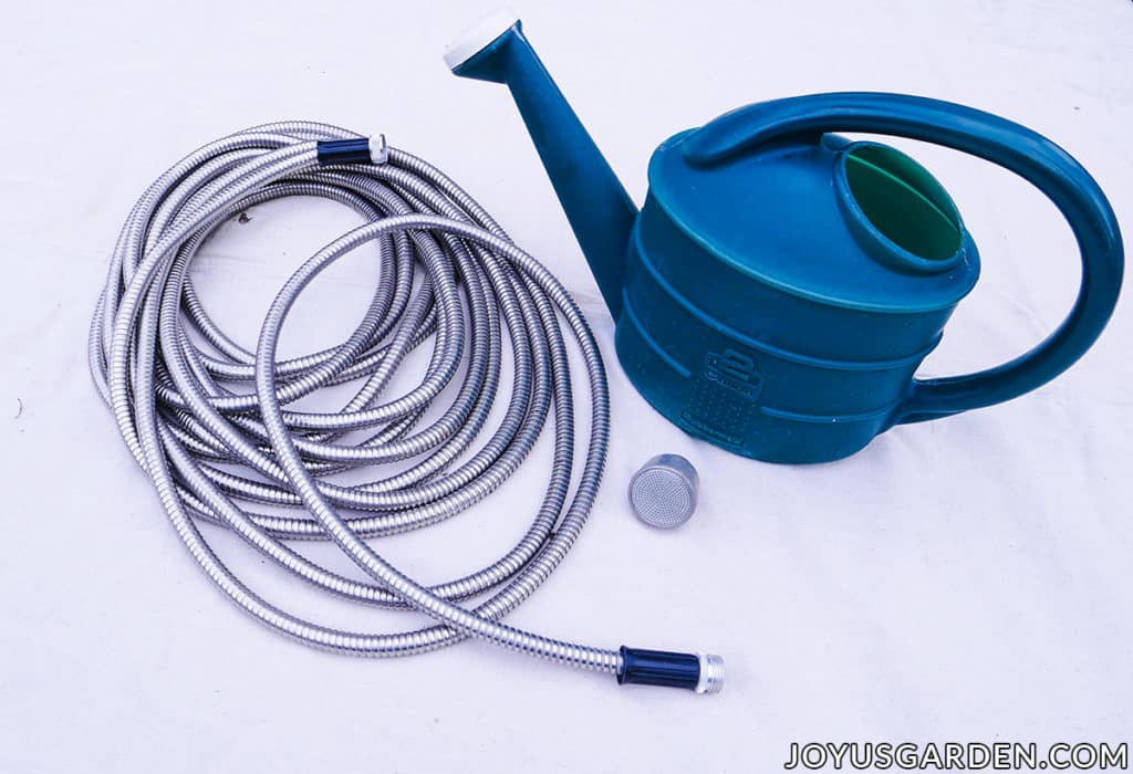An aluminum hose, nozzle & watering can used for gardening.
