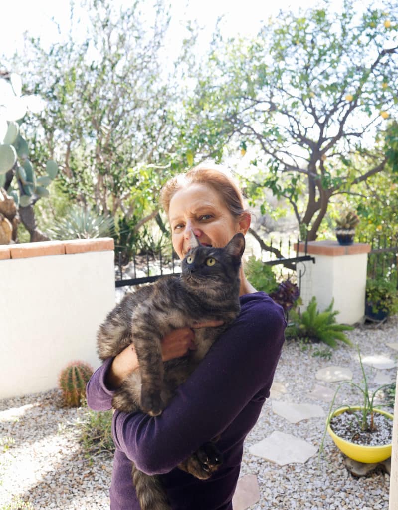 nell foster holds her grey striped kitty Riley in her garden