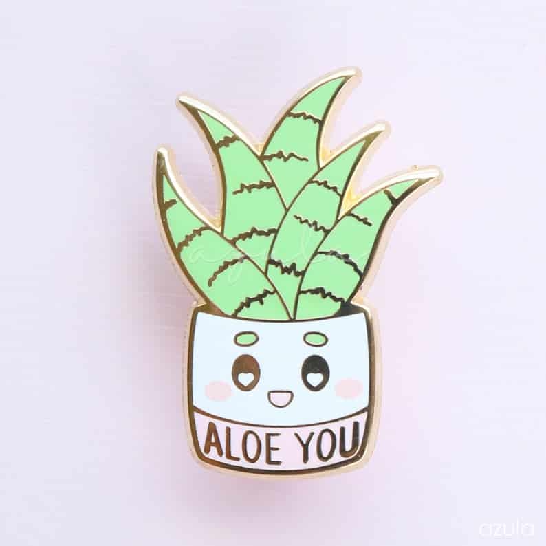 a pin shaped like an Aloe Vera plant that says "Aloe You"