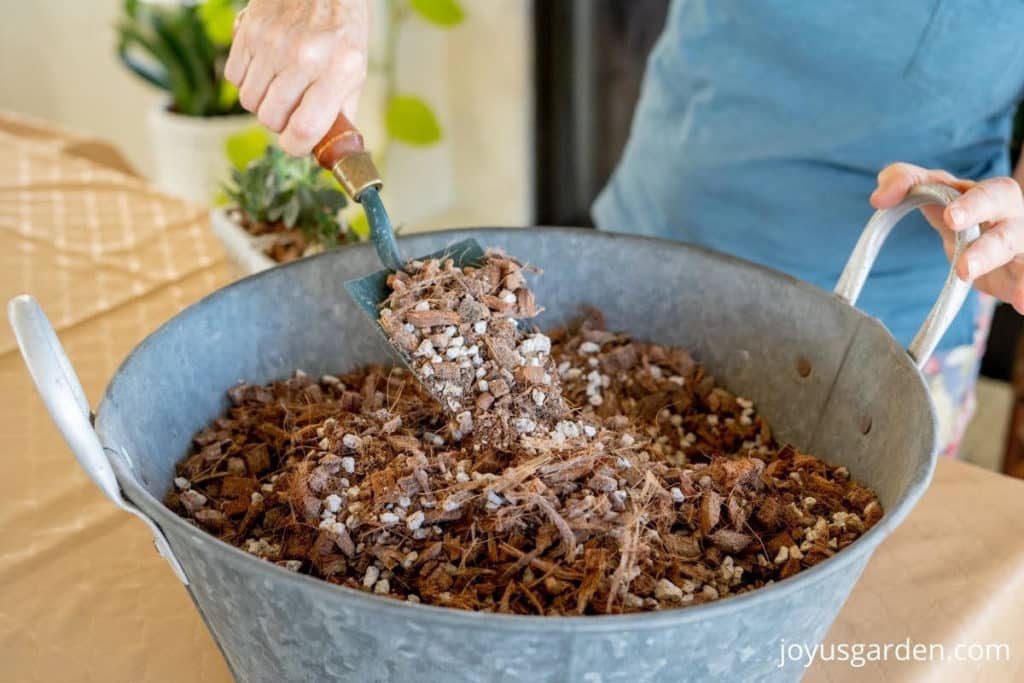 a trowel scoops succulent soil mix out of a tin bin