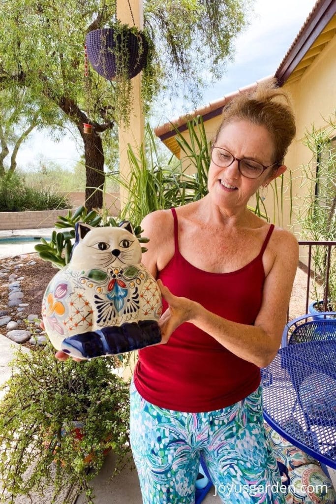 nell foster holds a cute talavera cat planter with a small jade plant planted in on her patio