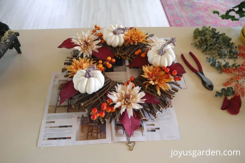 diy fall wreath with white pumpkins, red leaves, orange flowers, and orange berries