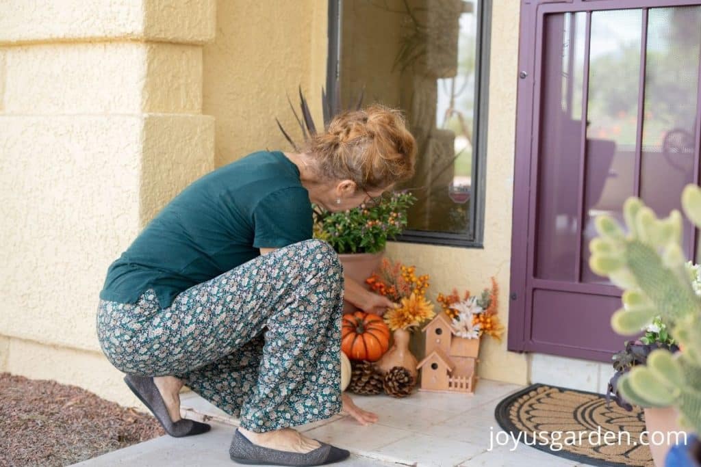 a women placing fall flowers on the front porch