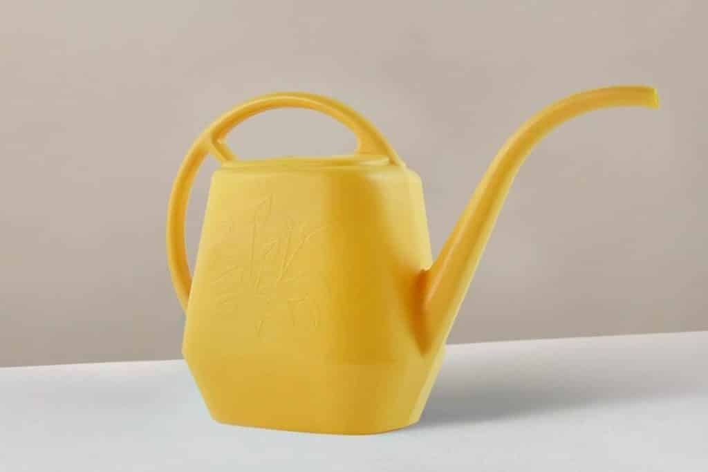 yellow plastic indoor watering can from the sill