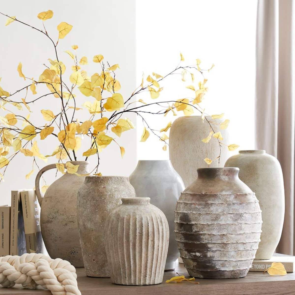seven earthenware vases shown in neutral soft tan and grey tones styled with some branches from pottery barn