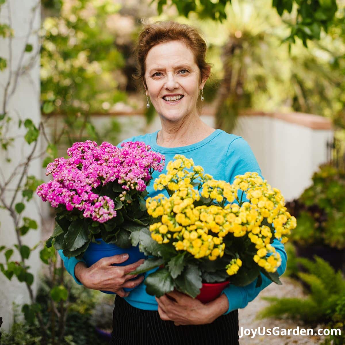 nell foster shown outdoors in turquoise top holding two kalanchoes in pink and yellow 