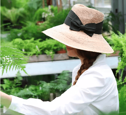 Woman wearing a sun hat with ribbon from anthropologie.