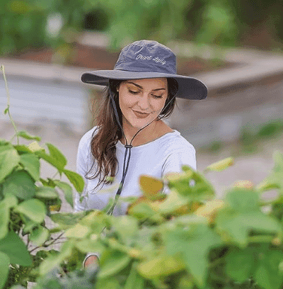 Woman wearing a wide brimmed sun hat in her garden hat from amazon.